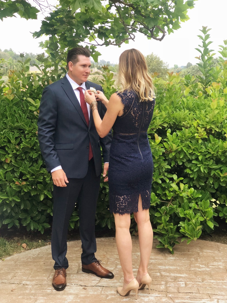 Woman adjusts boutonniere on a man in a suit outdoors