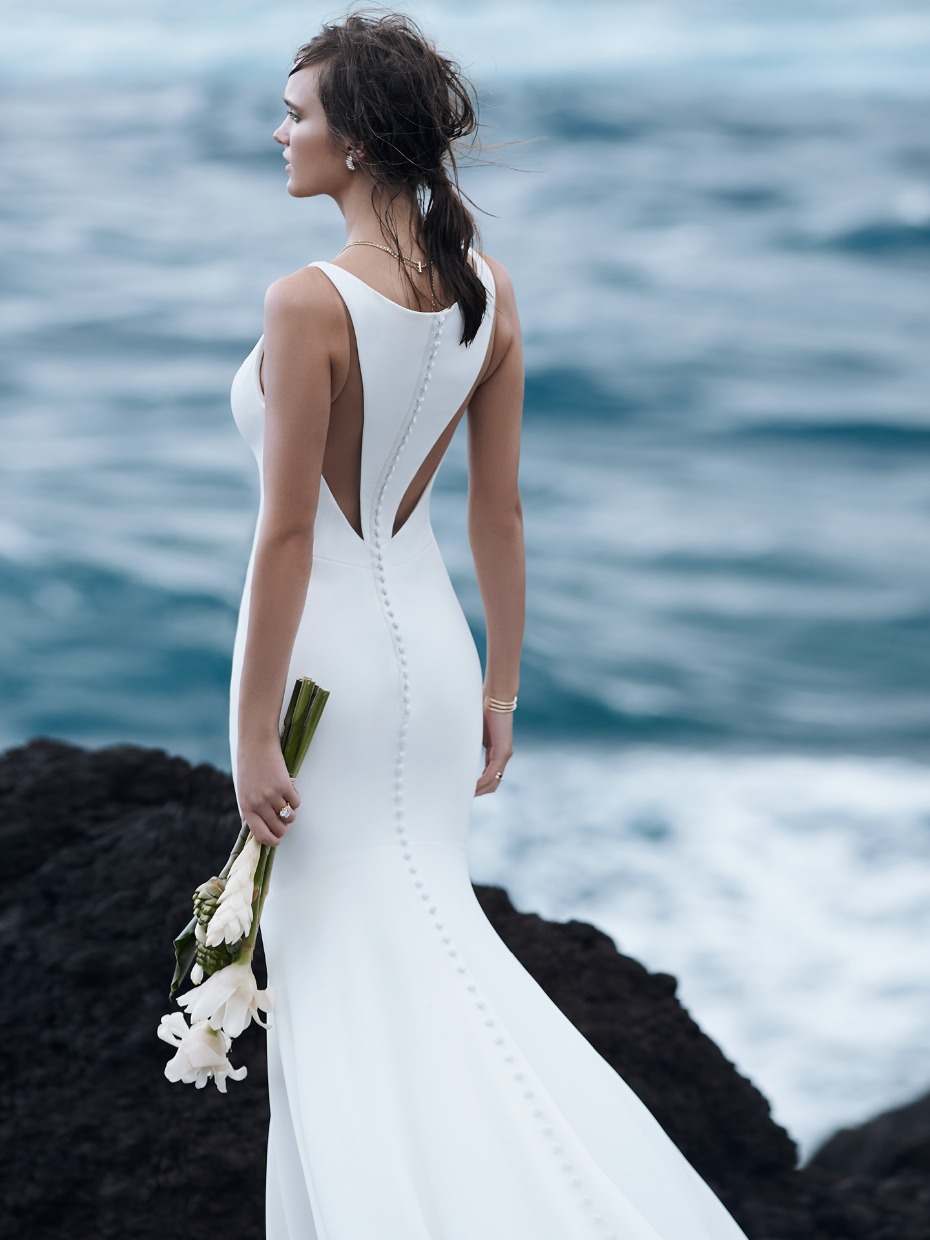 Bride in elegant white wedding dress looking at the ocean