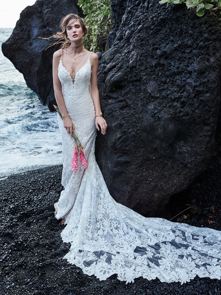 Bride in elegant lace wedding dress at beach with floral details