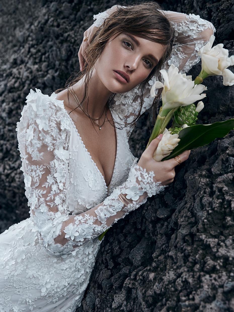 Elegant woman in white floral dress with flowers, looking at the camera