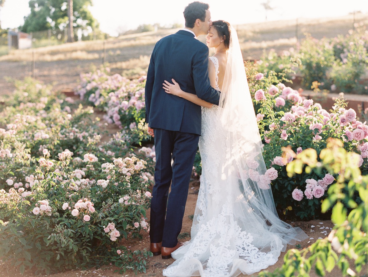 Newlyweds embrace in a rose garden on their wedding day