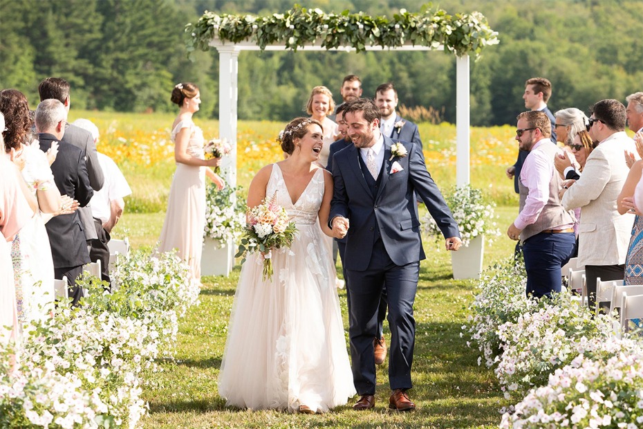 Newlyweds joyfully walk down aisle after outdoor wedding ceremony