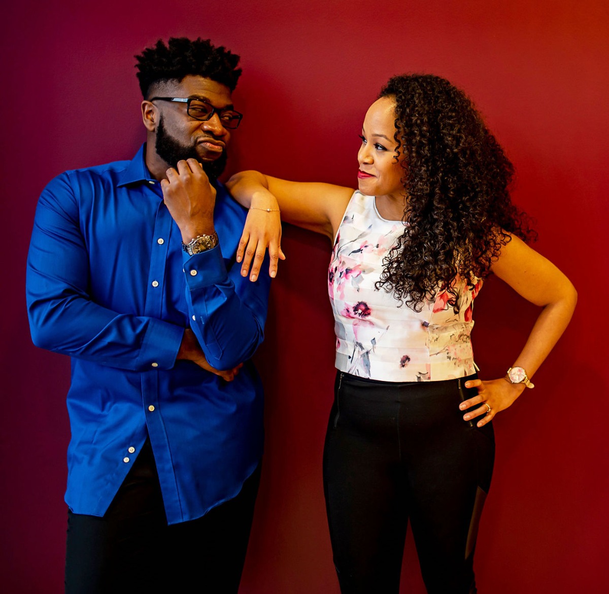 Couple leaning against a red wall, deep in thought and contemplation