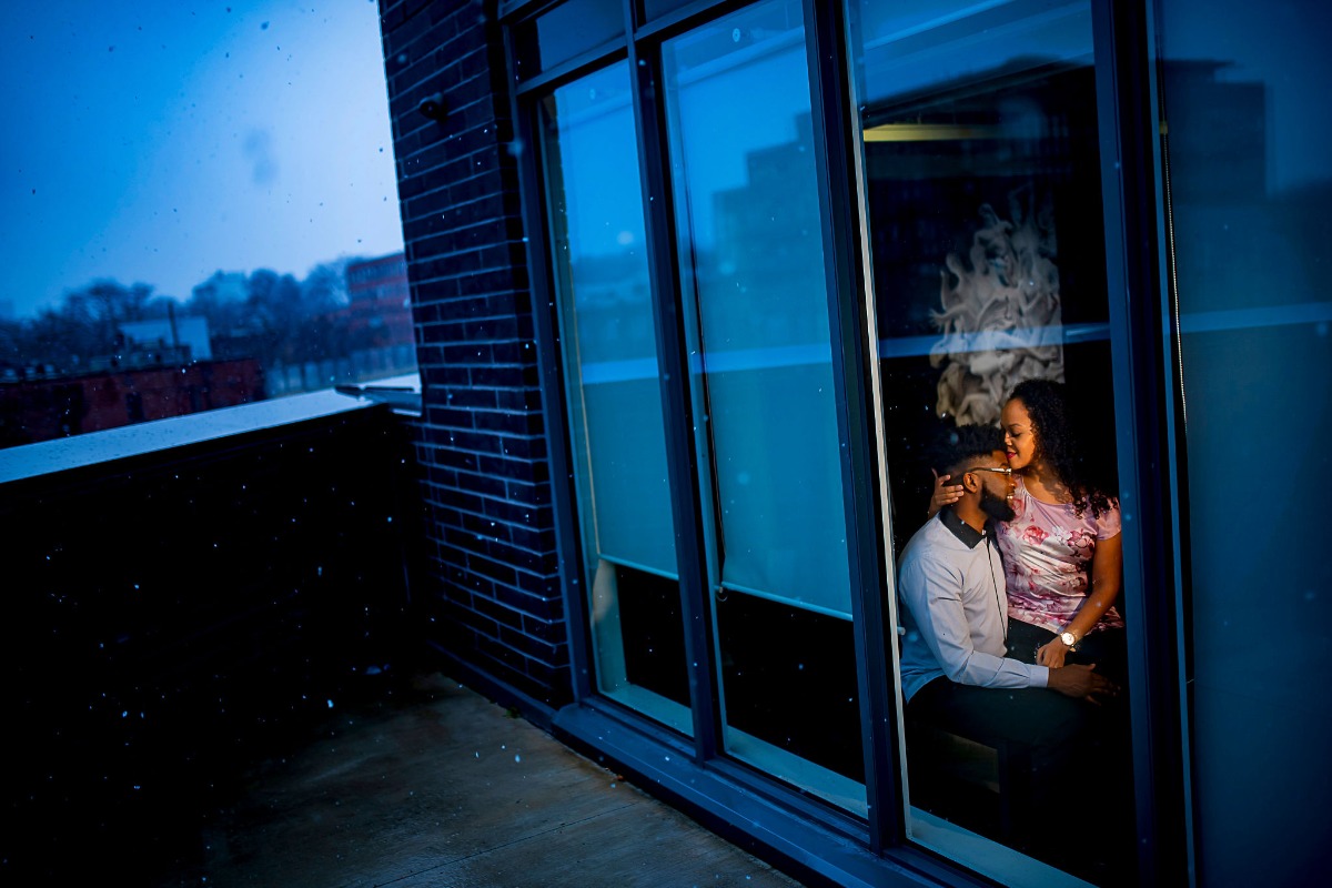 Couple kissing through the window with snowy cityscape reflection