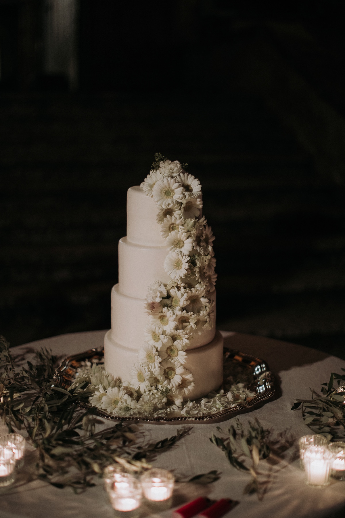 Elegant smooth buttercream wedding cake adorned with white daises