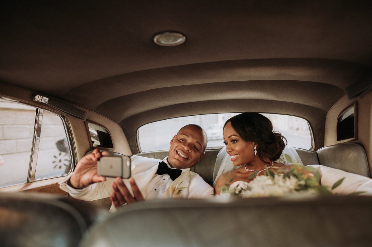 Bride and groom talking selfie in Rolls-Royce