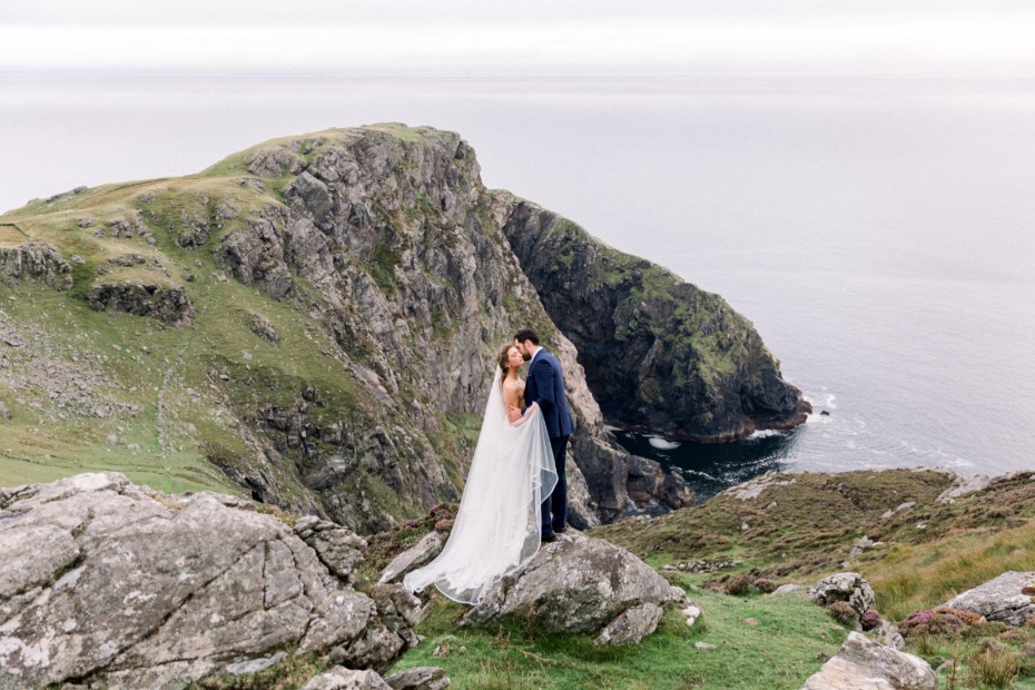 Couple kissing on a cliff at their outdoor wedding ceremony