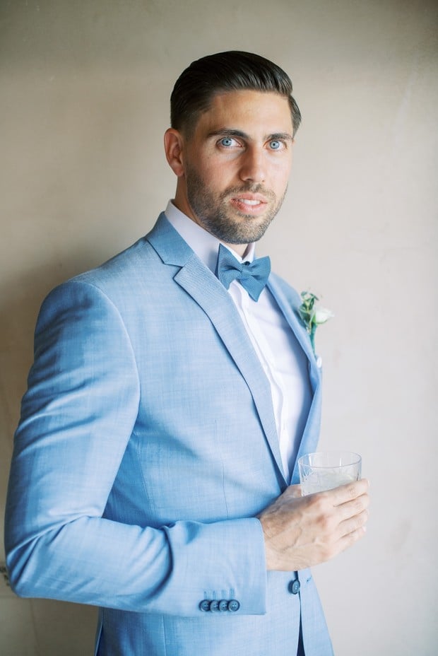 groom in light blue suit with bow tie