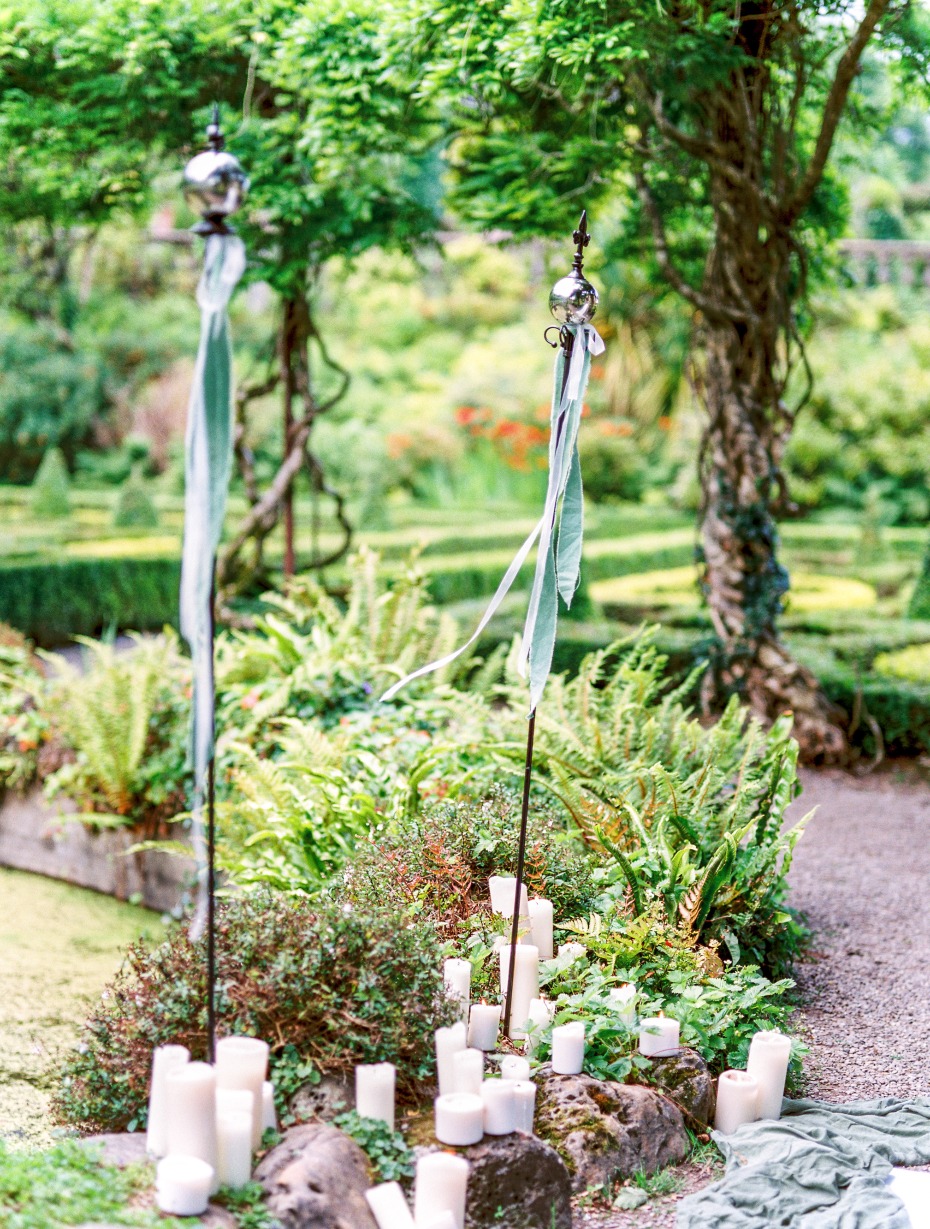 Outdoor wedding decor with candles and ribbons in a garden setting