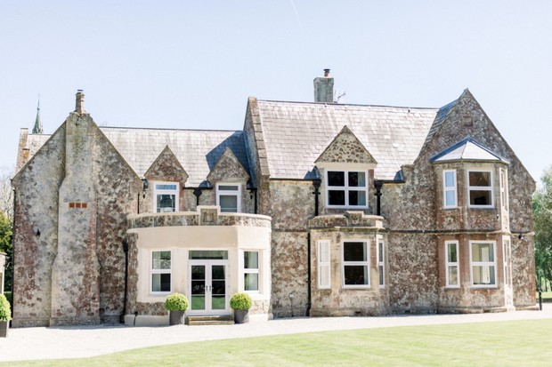 Stately stone mansion with a slate roof on a sunny day