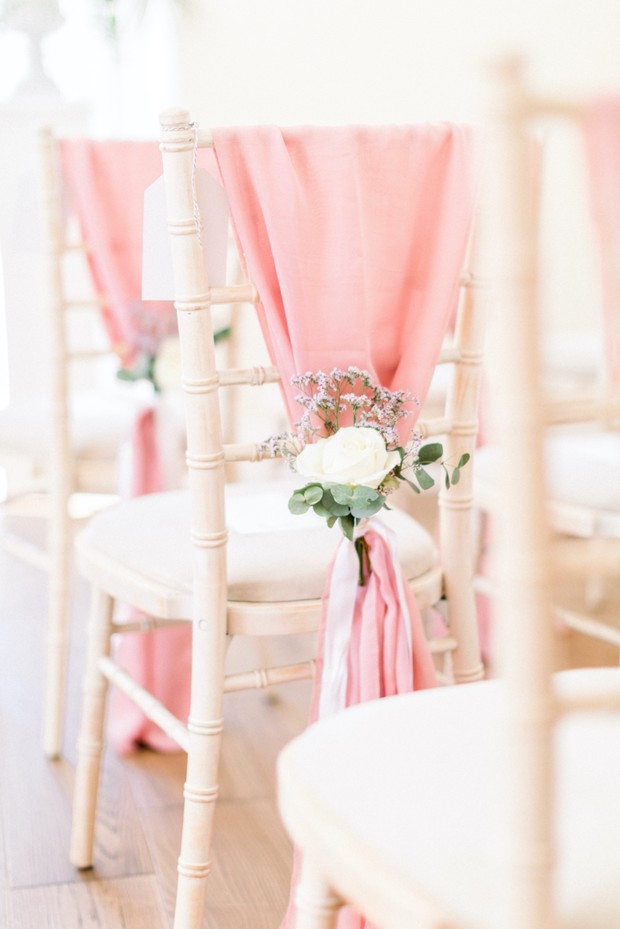 Wedding chairs decorated with pink fabric and flowers for ceremony