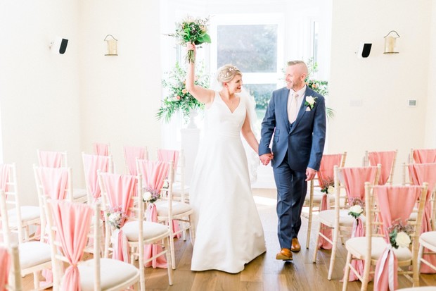 Newlyweds exit wedding ceremony holding hands with smiles