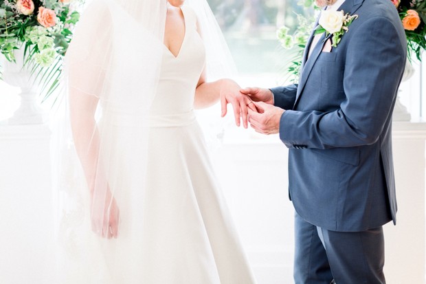 Groom places wedding ring on brides finger during ceremony
