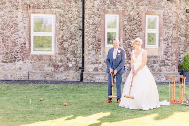 Bride and groom enjoy croquet on the lawn at their wedding