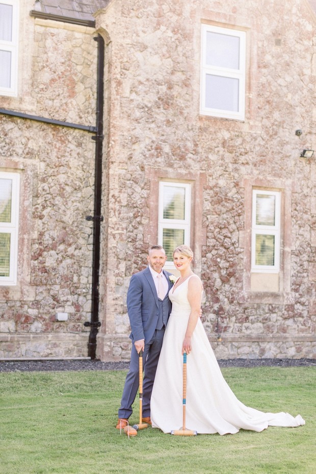 Newlyweds playing croquet on wedding day outside the venue