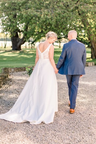 Bride and groom walk hand in hand at a beautiful outdoor wedding