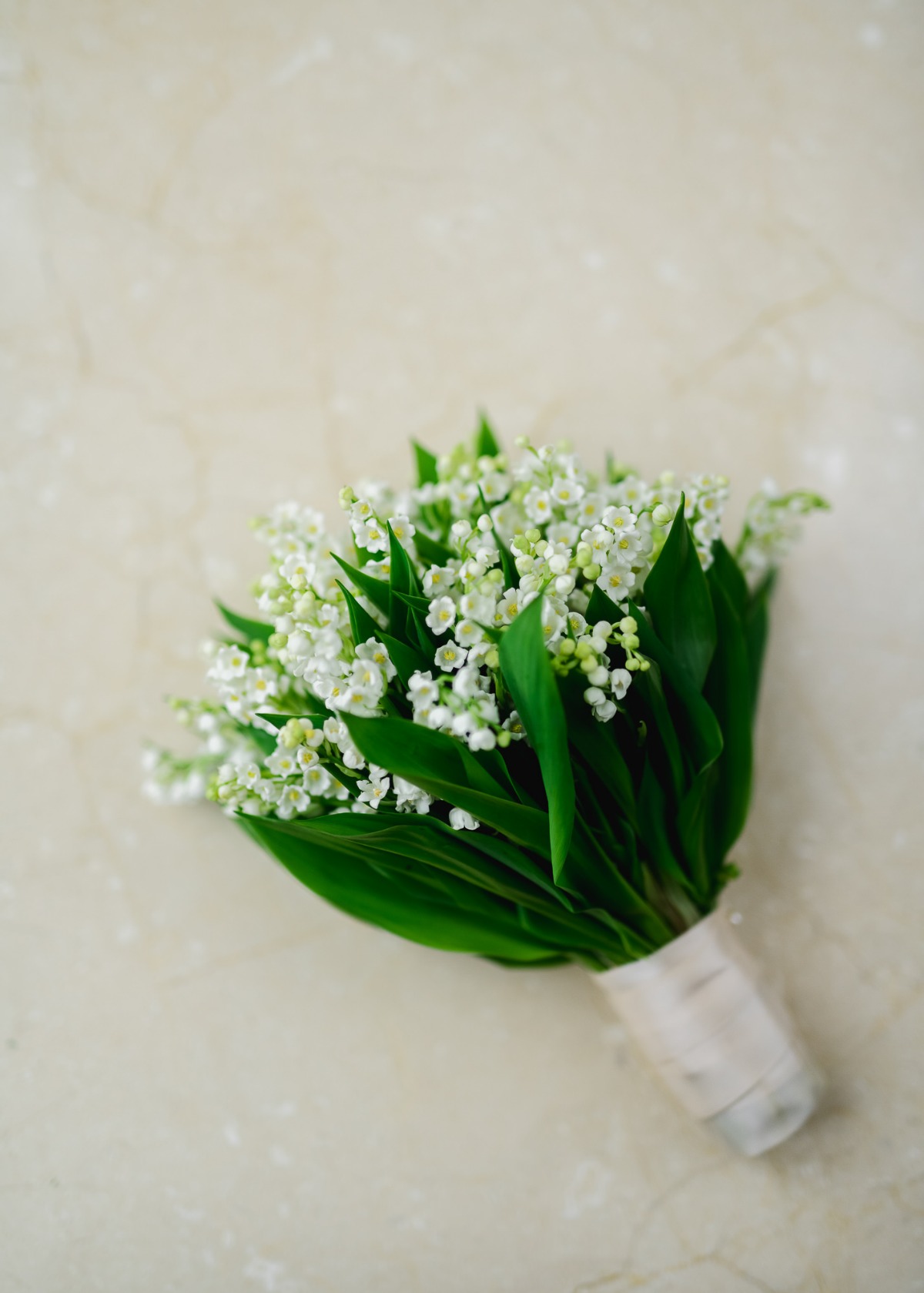 A delicate bouquet of white lily of the valley on a marble surface