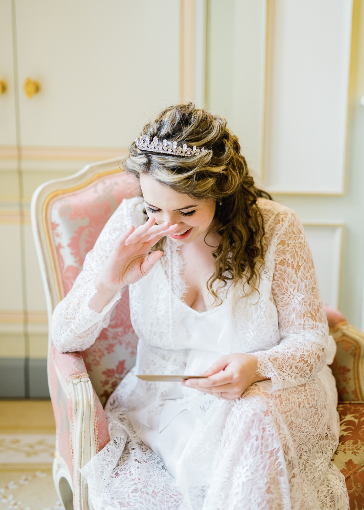 Bride in lace dress cries happy tears reading card