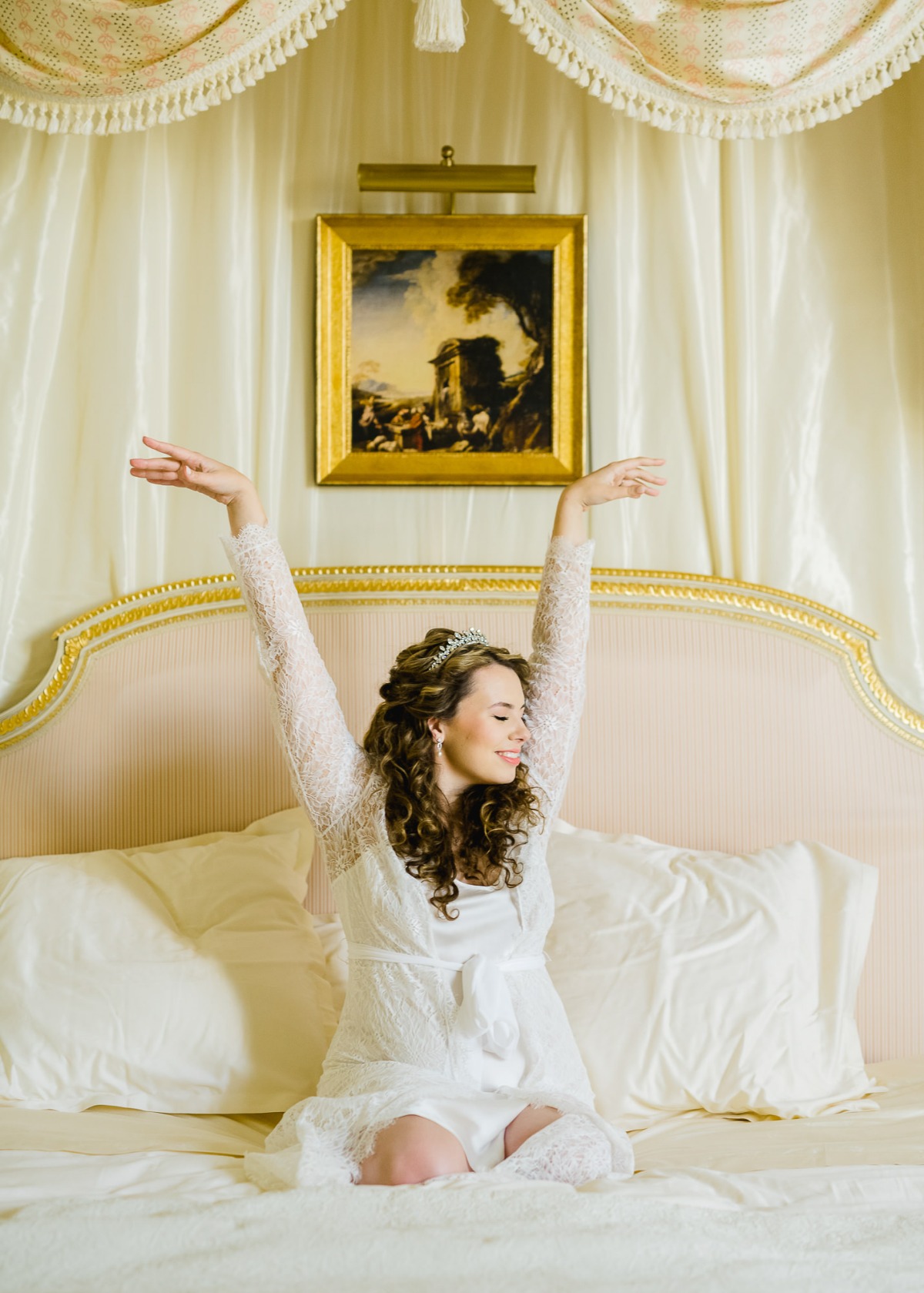 Happy bride in a luxurious bed stretching her arms up