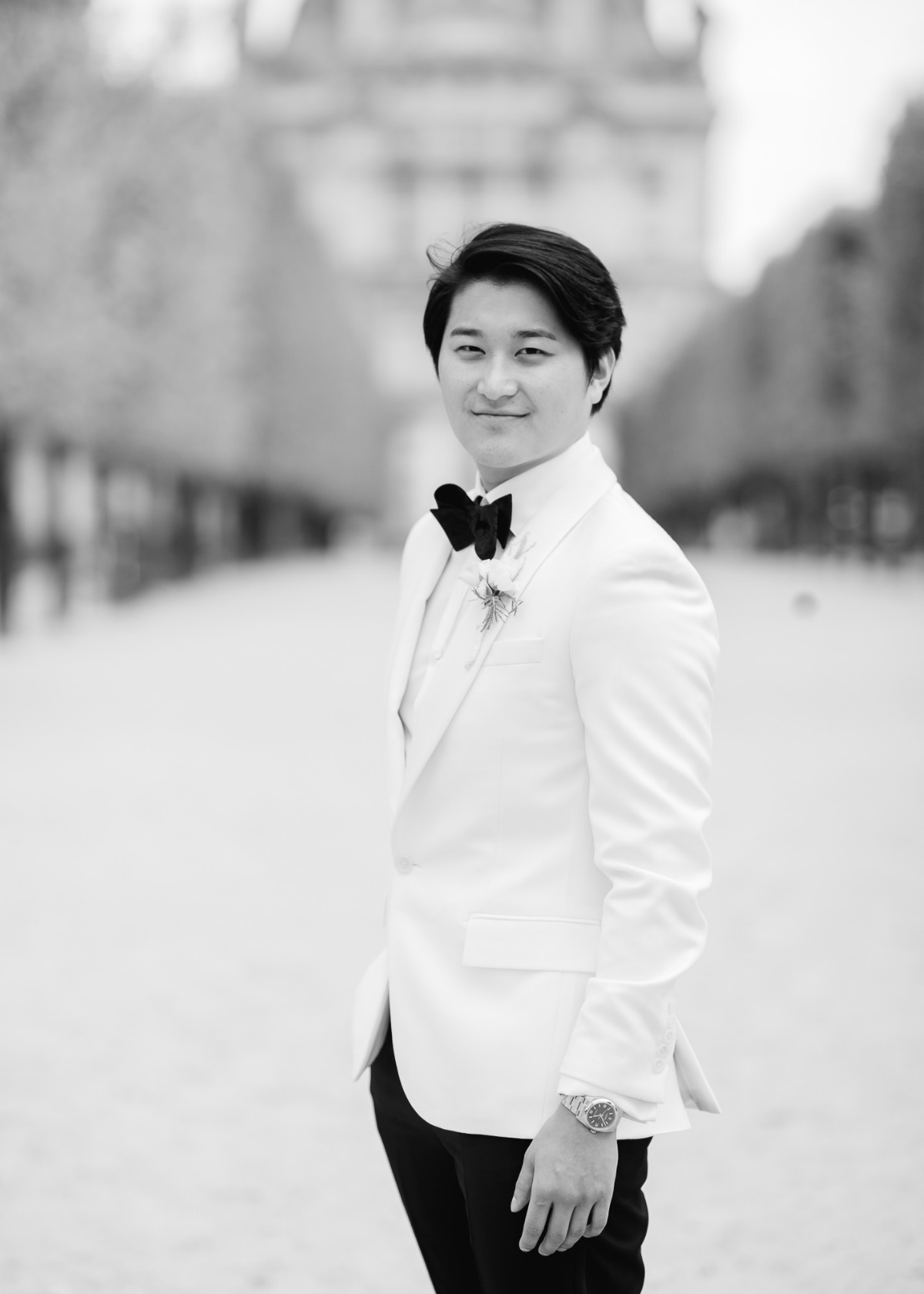 Elegant groom in white suit posing for a photo shoot outside