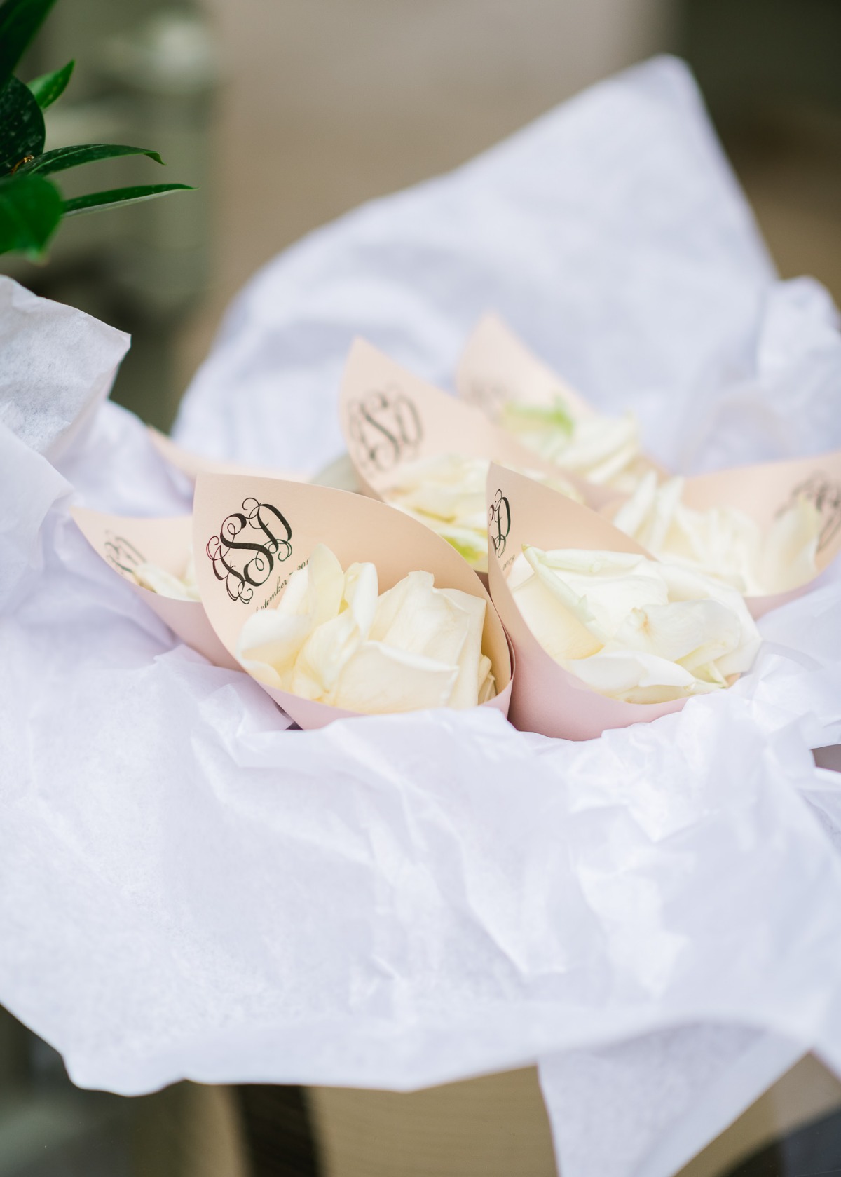 Rose petals in monogrammed cones for a wedding ceremony