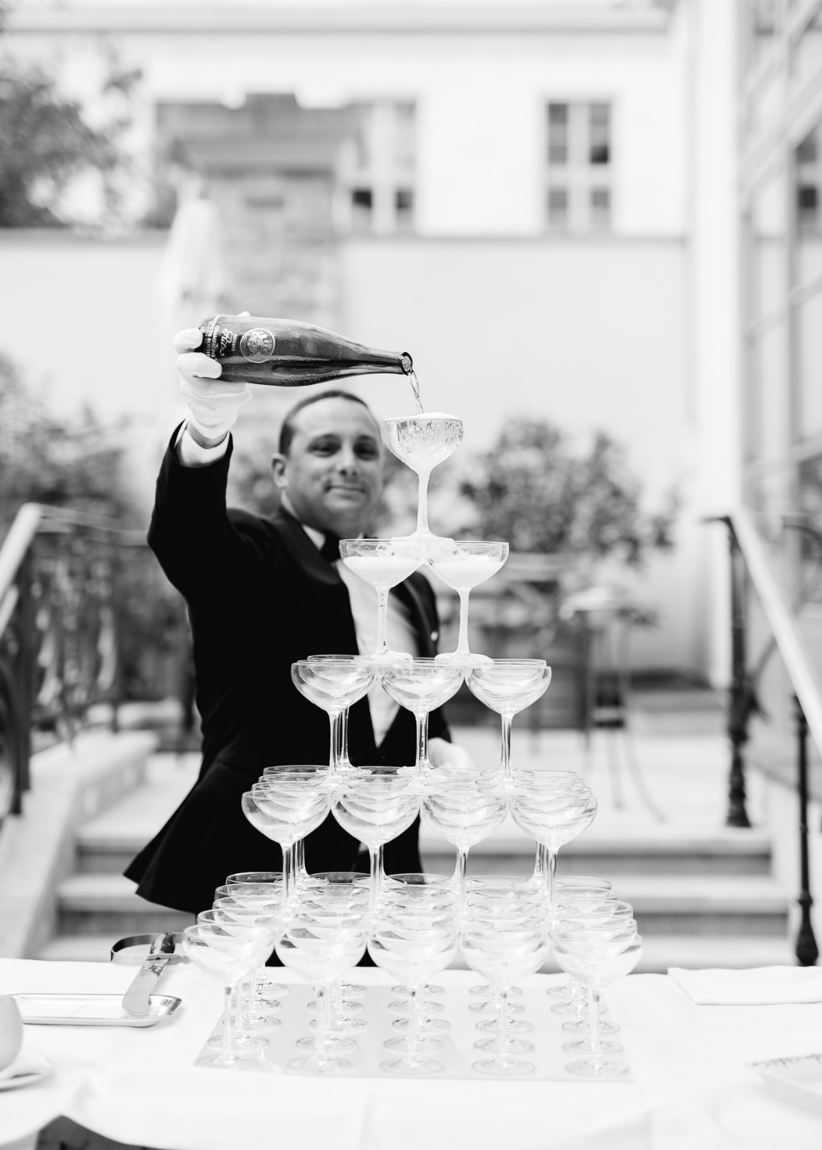 Server pours champagne into a tower of glasses at an event