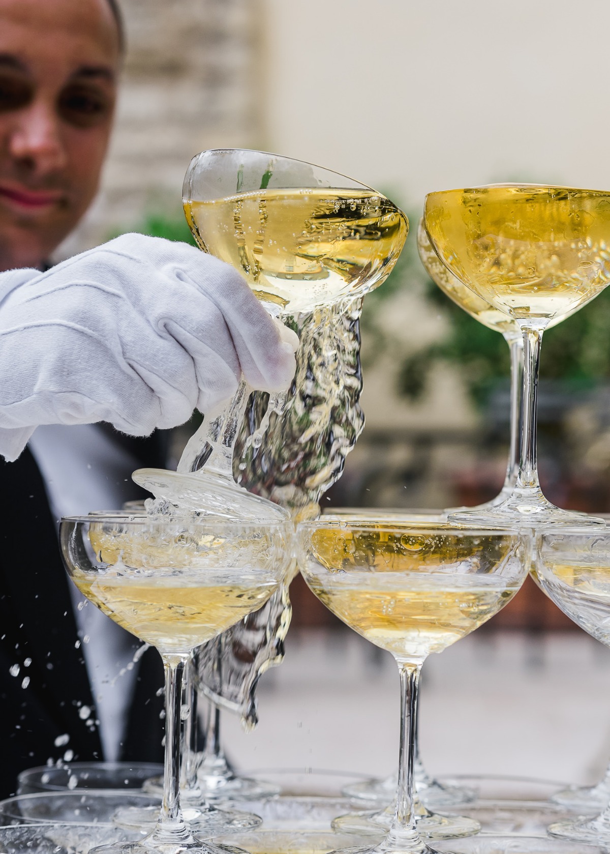 Waiter pouring champagne into a pyramid of glasses