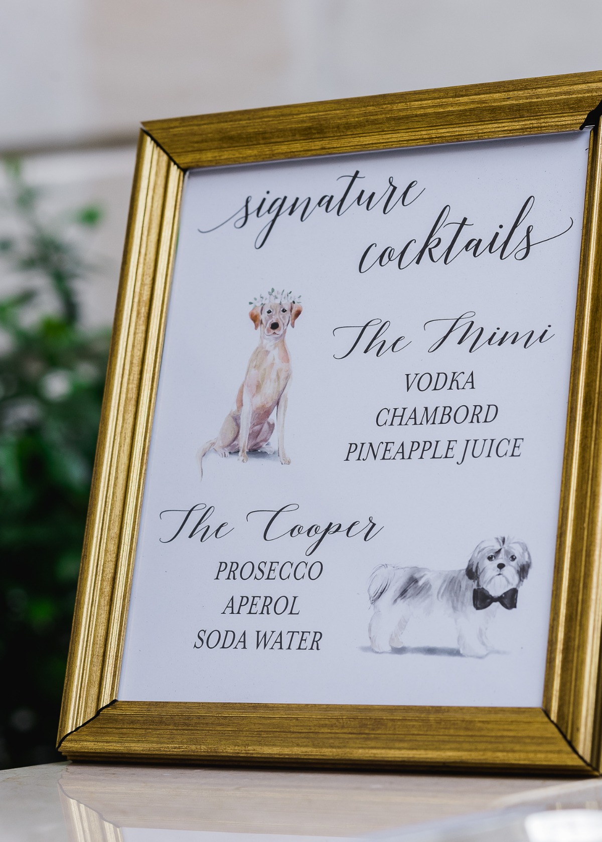 Signature cocktail menu with dog illustrations in a gold frame