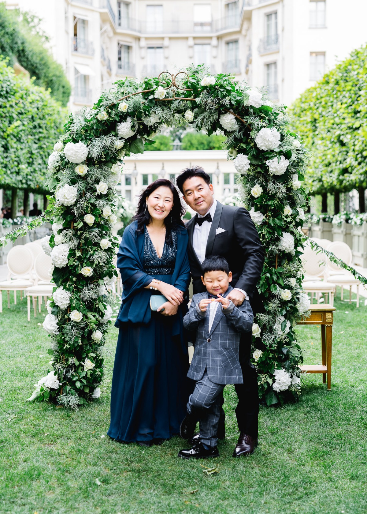 Family posing happily for a photo under a flower arch outdoors
