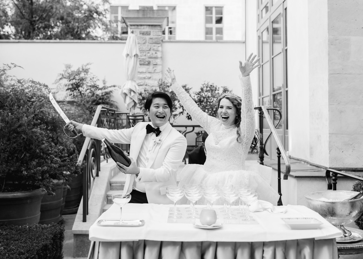 Newlyweds celebrate with champagne and a sword, joyful wedding day!