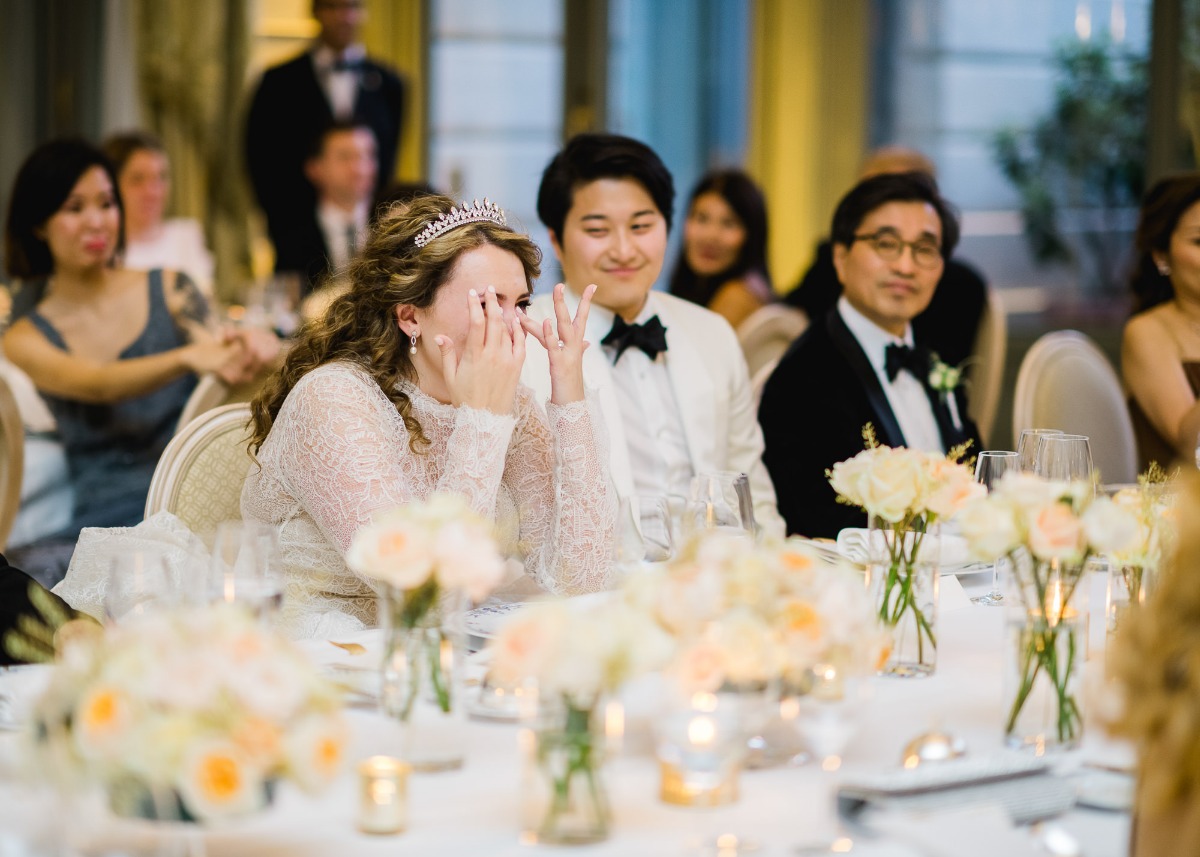 Bride wipes a tear during wedding reception with guests