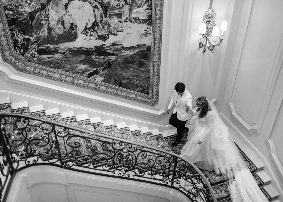 Bride and groom walking down a grand staircase on their wedding day