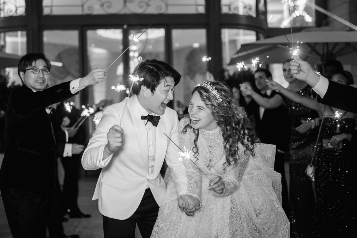 Newlyweds laugh amidst sparklers at their wedding celebration