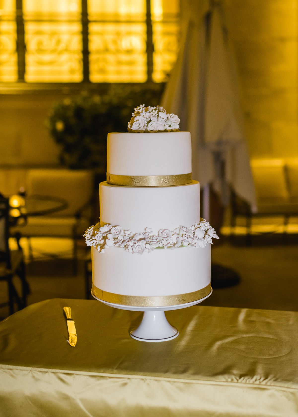 Elegant white wedding cake with gold accents and floral decor
