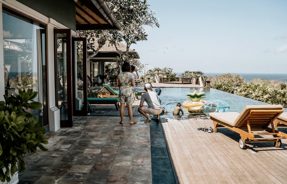 Family enjoying vacation by infinity pool with ocean view and sunshine