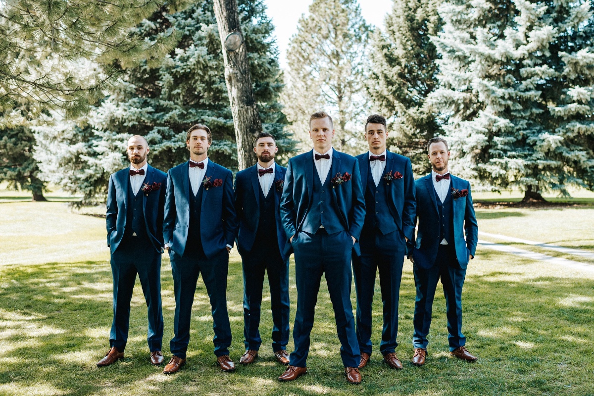 Groomsmen in navy suits with berry velvet bow ties