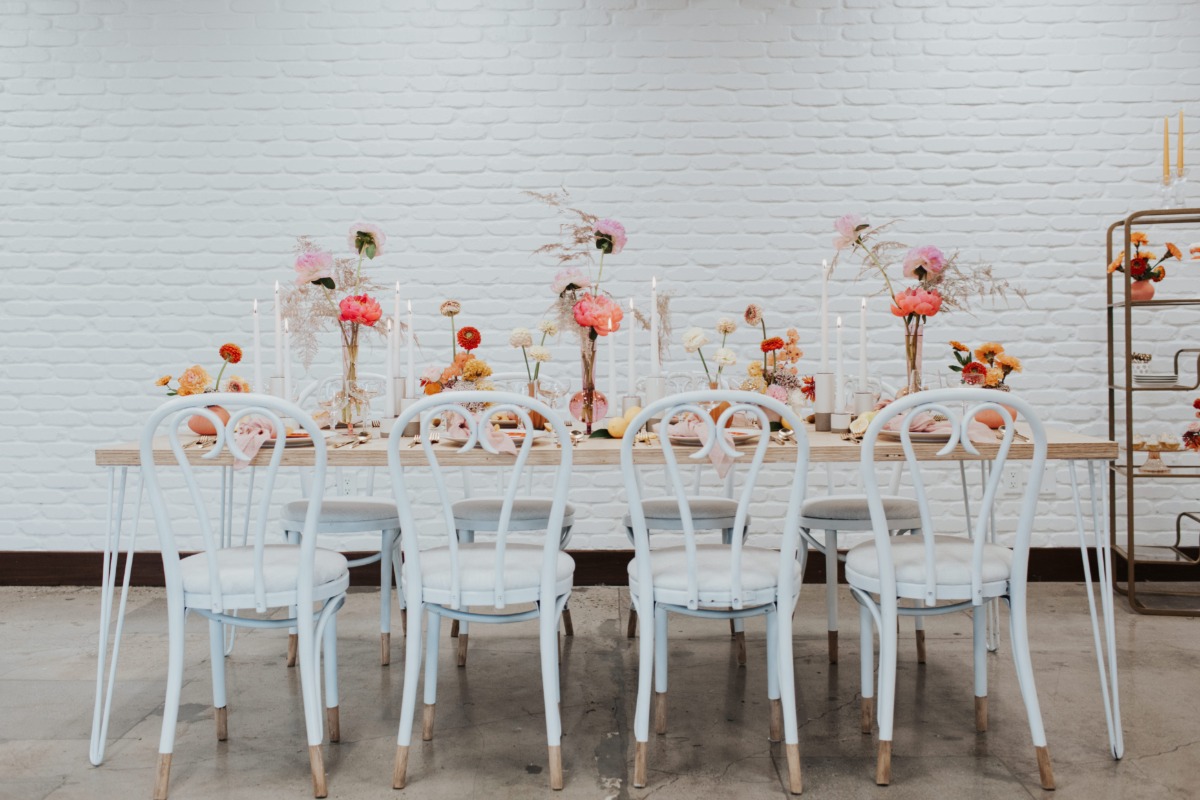 Elegant wedding table setting with flowers, candles, and white chairs