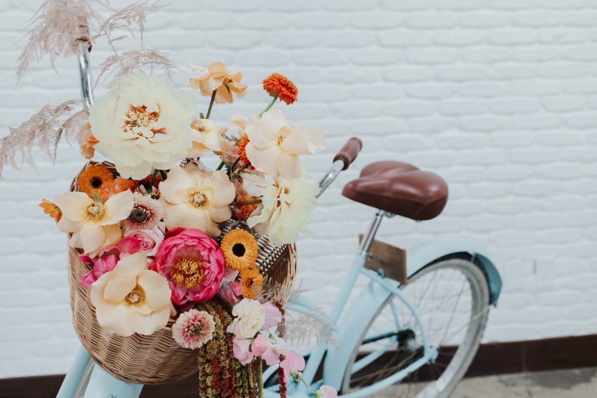 Vintage blue bicycle with a woven basket full of colorful flowers