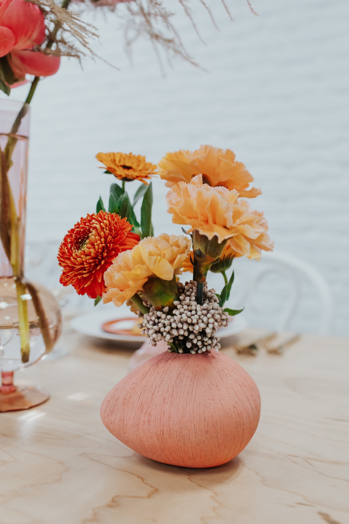 Orange and coral flowers arranged in a pink vase, simple elegant design