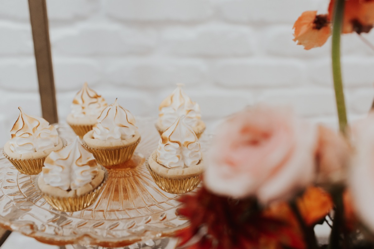 Delicious mini lemon meringue pies on a vintage glass plate, closeup