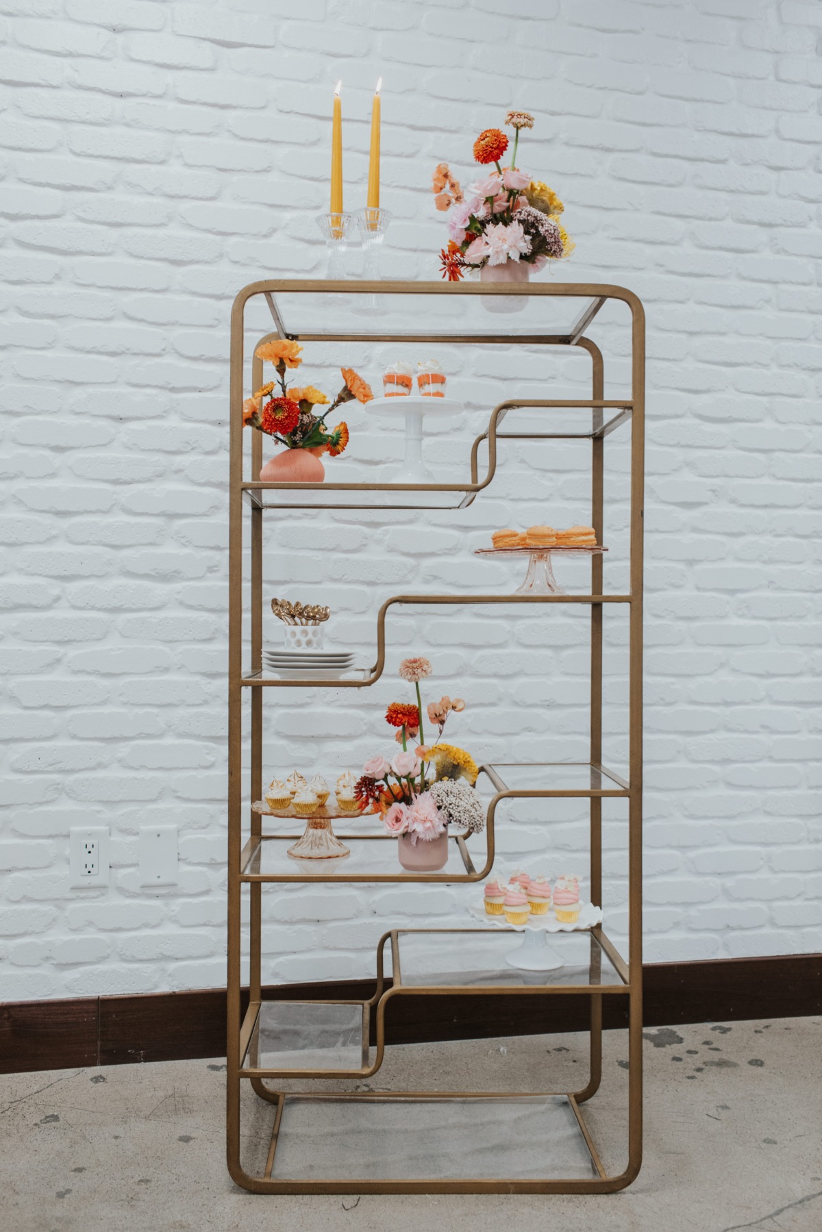 Elegant display shelf with flowers and baked goods, perfect for a party