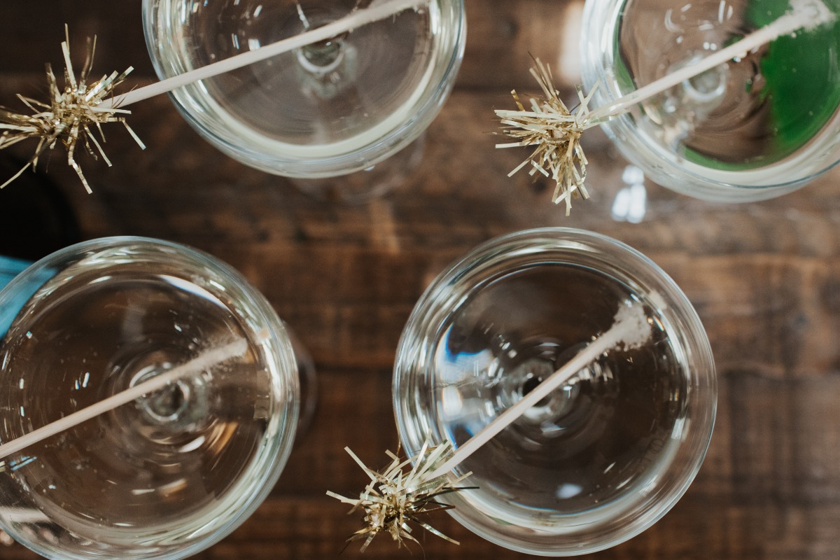 Overhead shot of cocktail glasses with golden straws on wood table