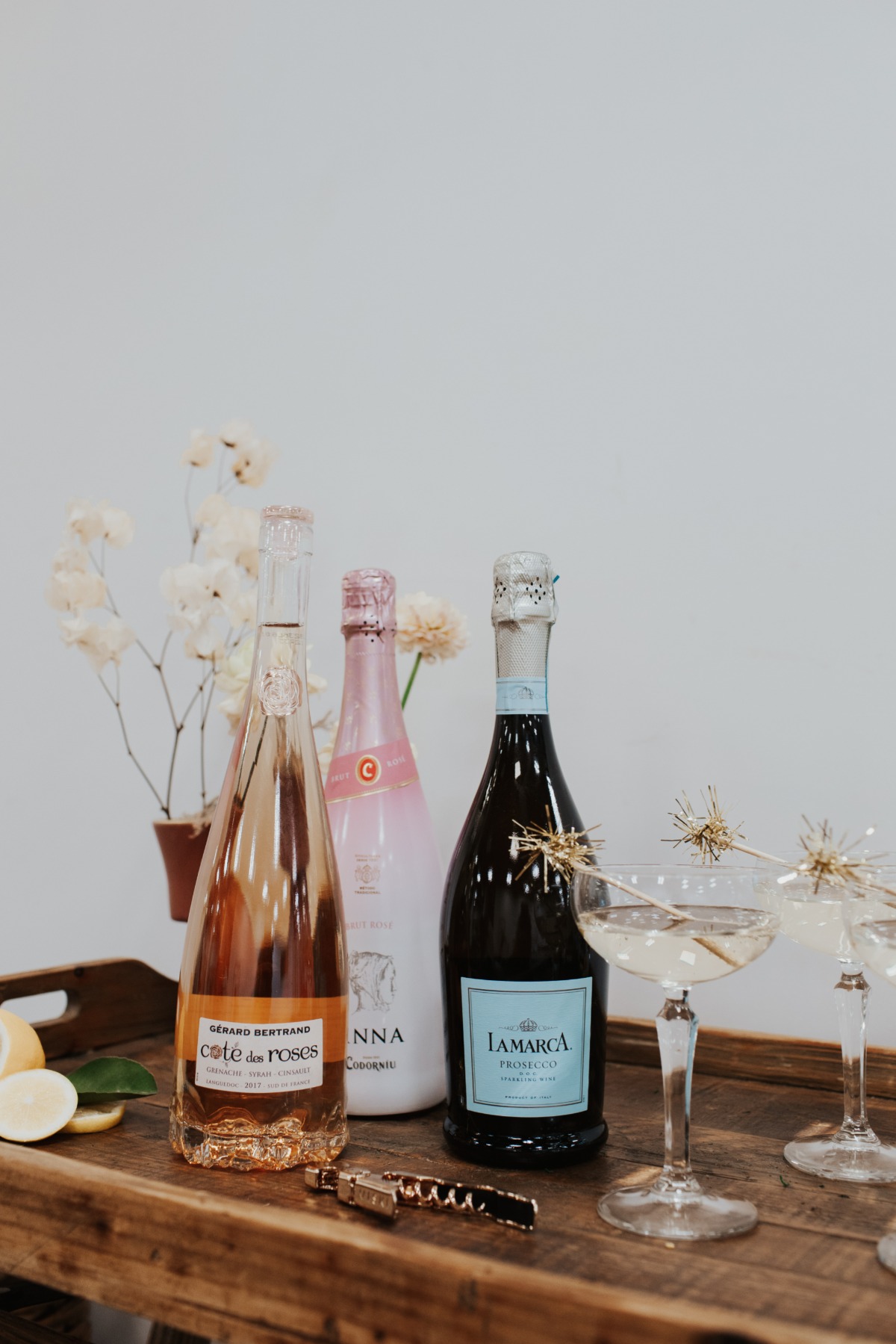 Bottles of rose and Prosecco, cocktails, and a wooden tray