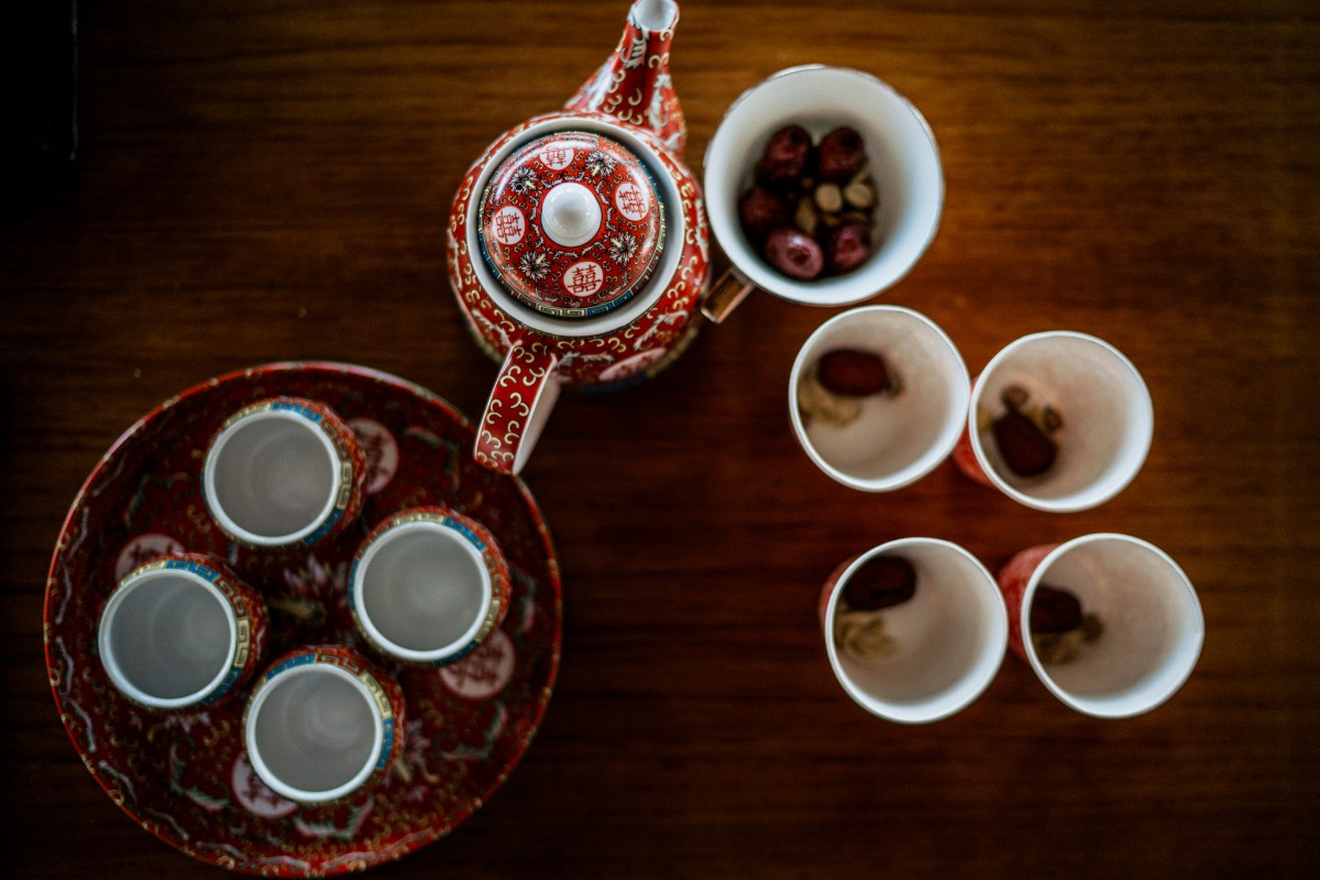 Overhead shot of an ornate tea set with cups and fruits