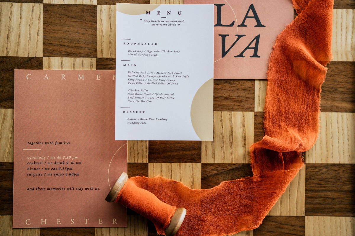 Wedding invitation design with menu and orange ribbon on wood