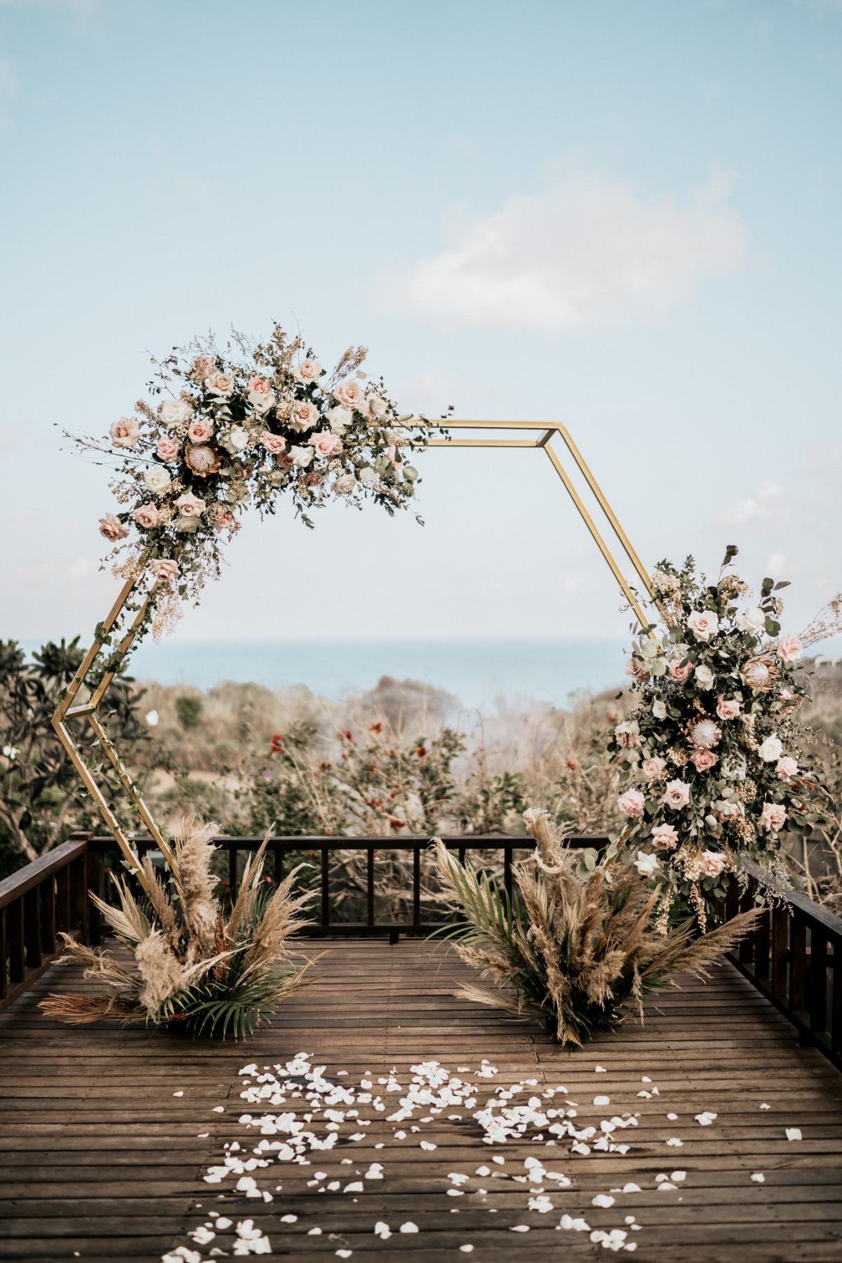Wedding arch adorned with flowers on a wooden deck