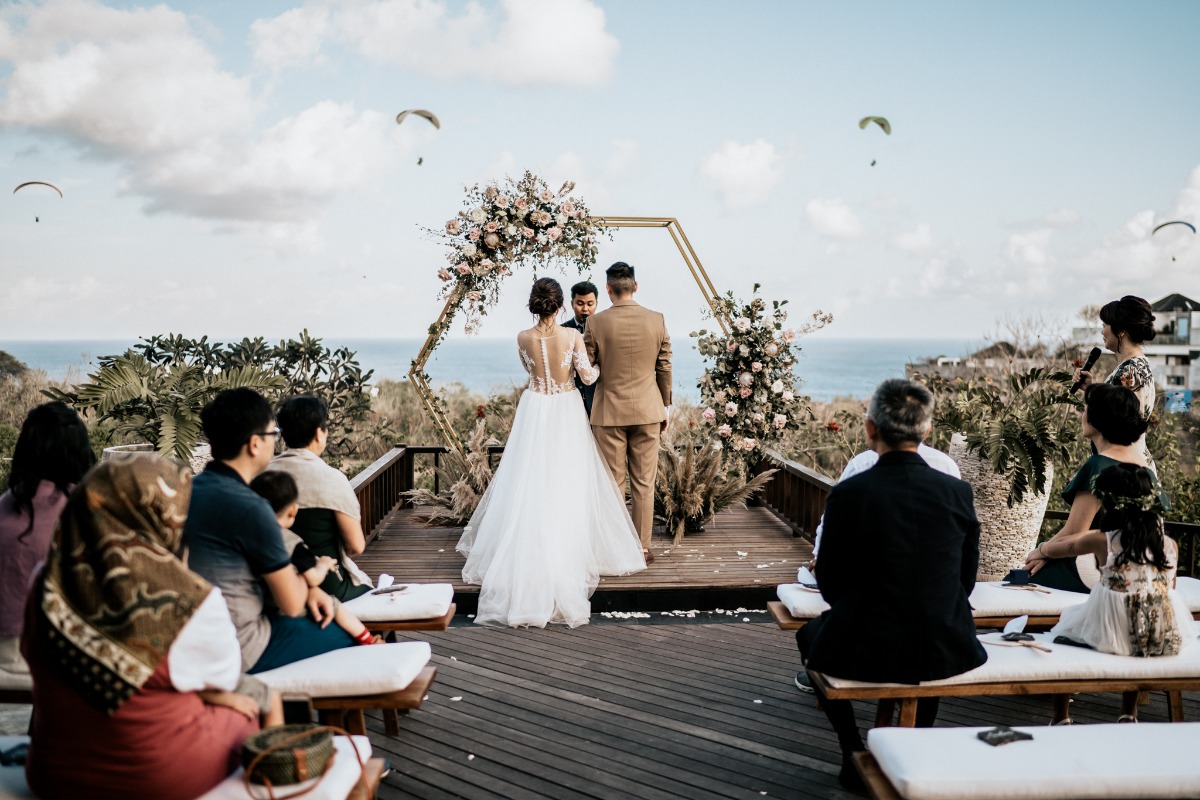 Romantic outdoor wedding ceremony with ocean view and paragliders