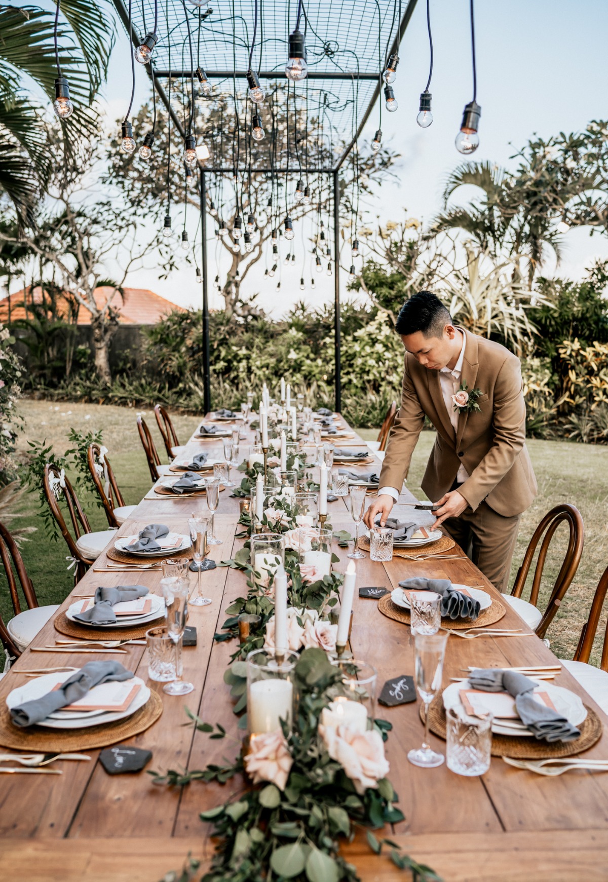 Man adjusts place setting at rustic outdoor wedding table