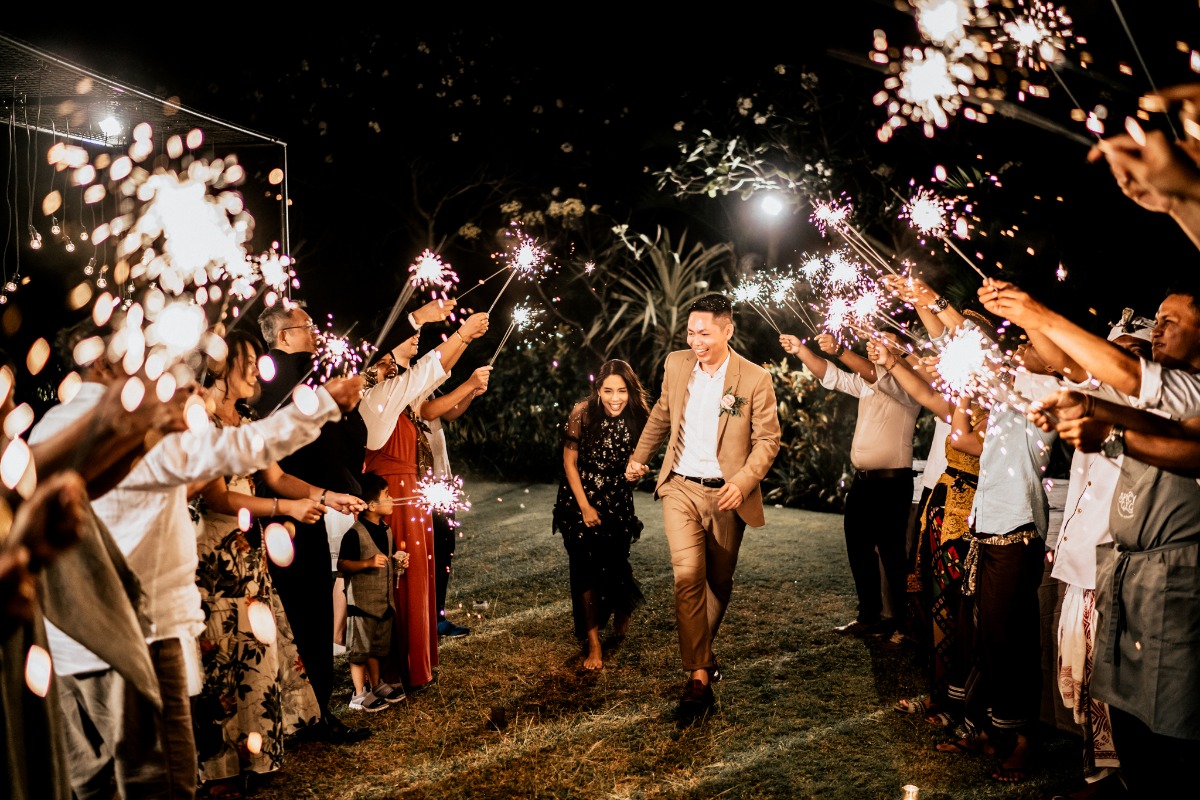 Joyful couple walks under a bright sparkler exit arch