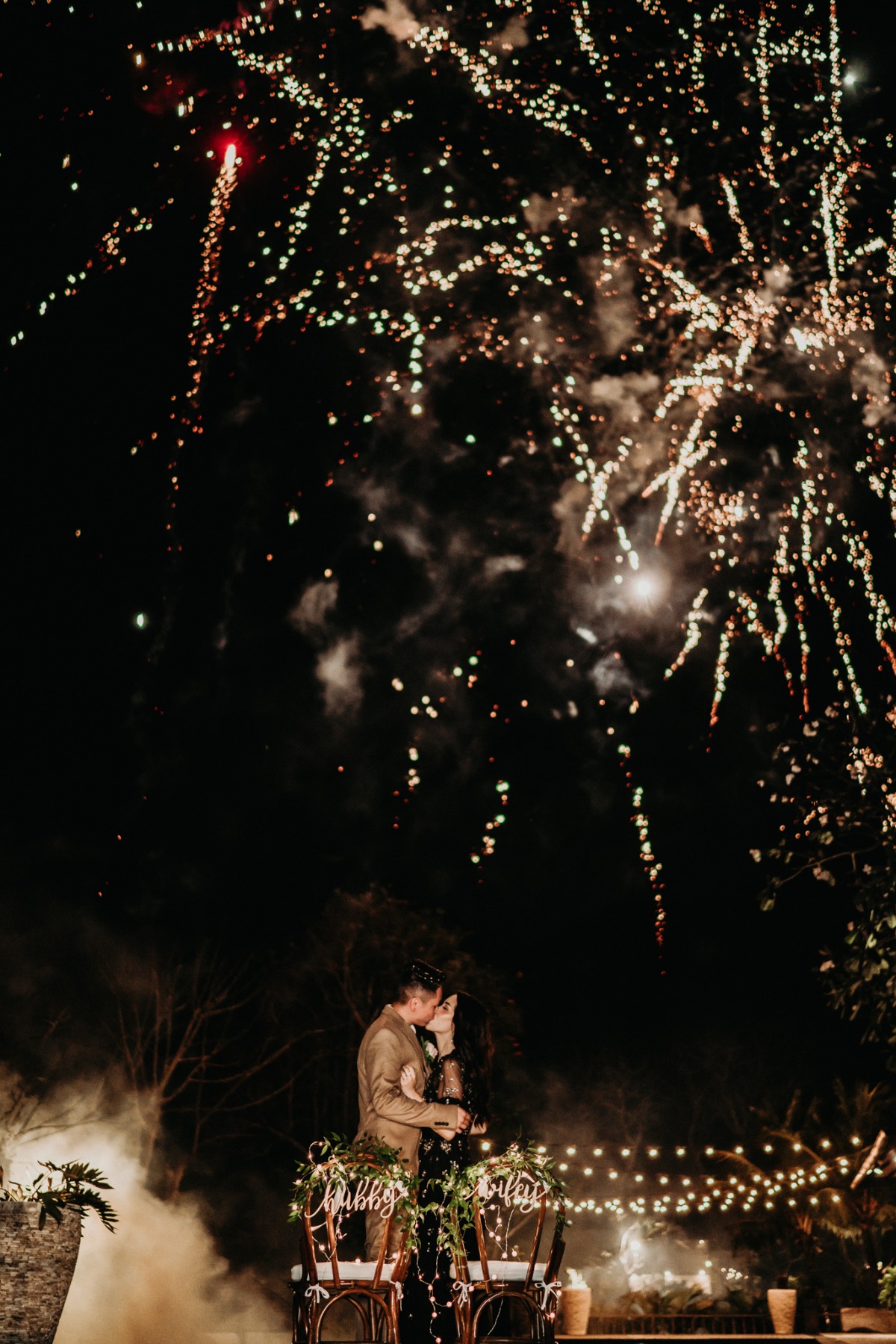 Newlyweds share a romantic kiss under fireworks display